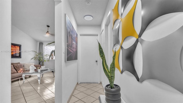 corridor featuring a textured ceiling and light tile patterned floors