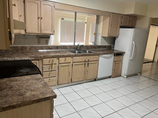 kitchen featuring light tile patterned flooring, tasteful backsplash, white appliances, light brown cabinetry, and sink