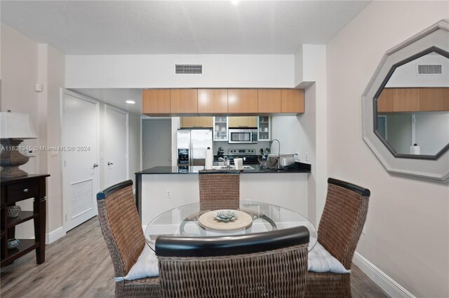 kitchen with light hardwood / wood-style flooring, kitchen peninsula, sink, and stainless steel appliances