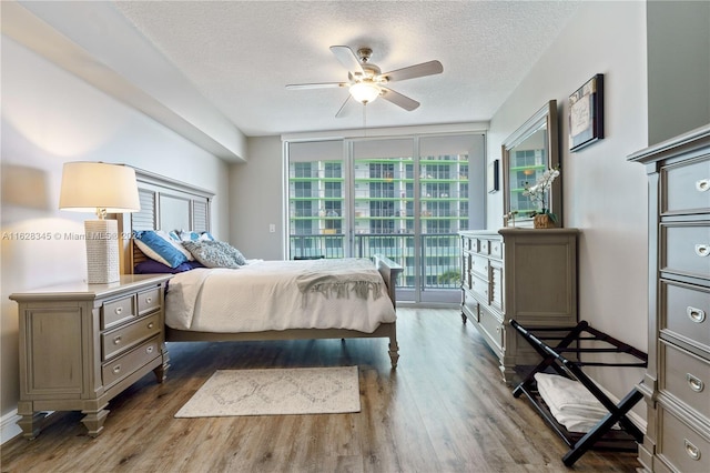 bedroom with ceiling fan, dark hardwood / wood-style floors, a textured ceiling, and access to outside