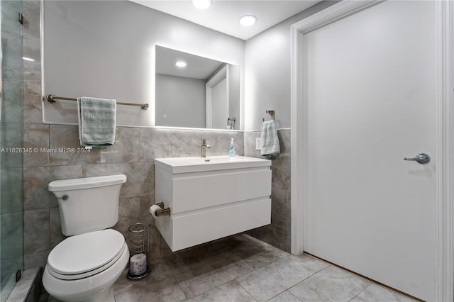 bathroom with toilet, vanity, and tile walls