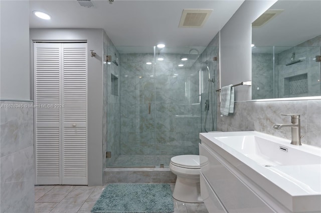 bathroom featuring tile patterned floors, toilet, tile walls, an enclosed shower, and vanity