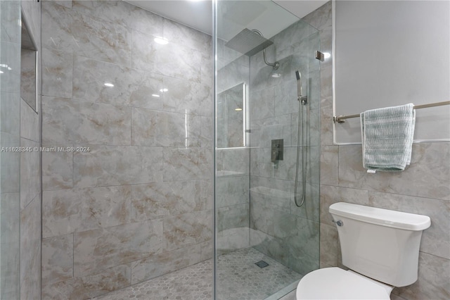 bathroom with tile walls, a tile shower, and toilet