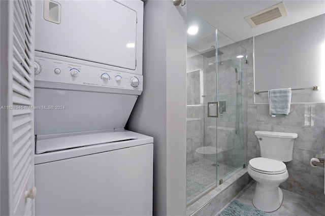 bathroom featuring toilet, an enclosed shower, and stacked washer and dryer