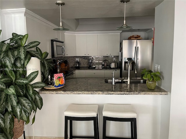 kitchen featuring appliances with stainless steel finishes, tasteful backsplash, white cabinets, decorative light fixtures, and crown molding