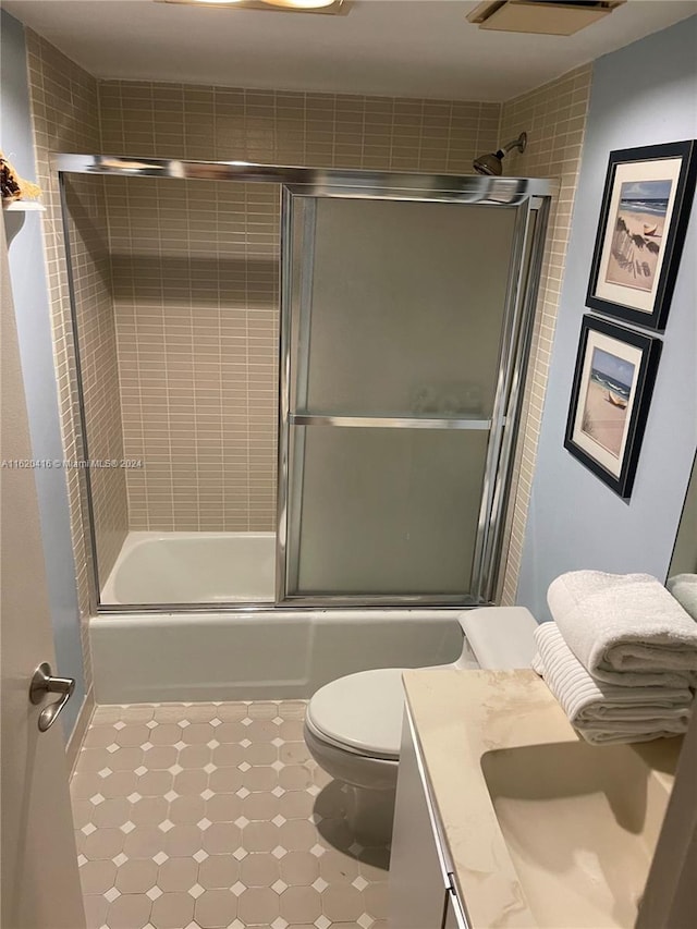 full bathroom with tile patterned flooring, toilet, vanity, and enclosed tub / shower combo