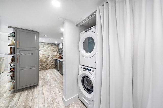 laundry room featuring light wood-type flooring and stacked washer / dryer