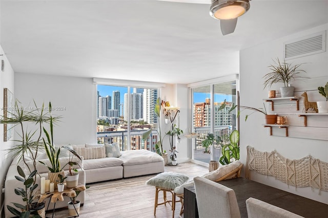 living room featuring light hardwood / wood-style flooring, expansive windows, and ceiling fan