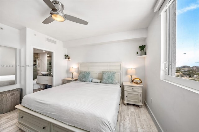 bedroom featuring ceiling fan, ensuite bathroom, and light wood-type flooring