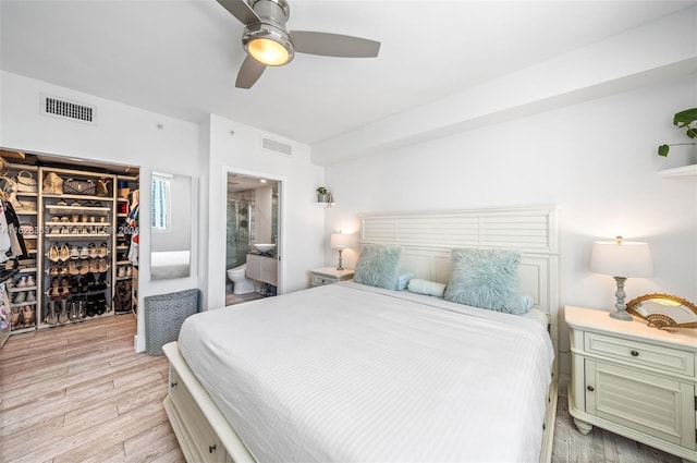 bedroom featuring ceiling fan, light hardwood / wood-style floors, and ensuite bath