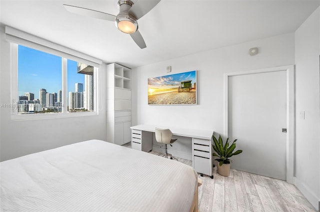 bedroom featuring ceiling fan, built in desk, and light wood-type flooring