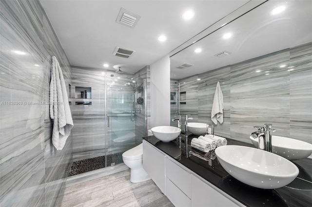 bathroom featuring toilet, tile walls, vanity, a shower with door, and hardwood / wood-style flooring