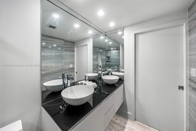 bathroom featuring vanity, a shower with shower door, wood-type flooring, and tile walls