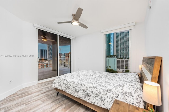 bedroom featuring hardwood / wood-style flooring, ceiling fan, expansive windows, and access to outside