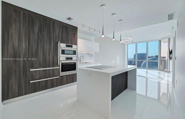 kitchen with decorative light fixtures, white cabinetry, multiple ovens, light tile patterned floors, and track lighting