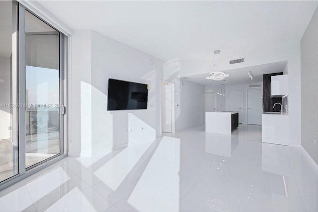 unfurnished living room featuring light tile patterned flooring and sink