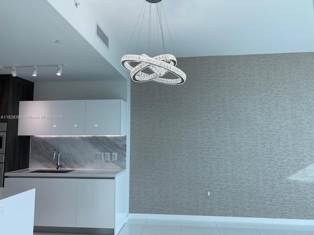 kitchen with decorative light fixtures, white cabinetry, sink, oven, and light tile patterned floors