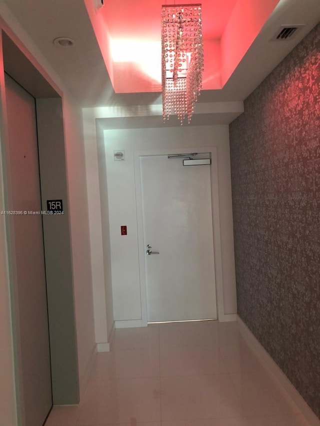 hallway featuring tile patterned floors and a chandelier