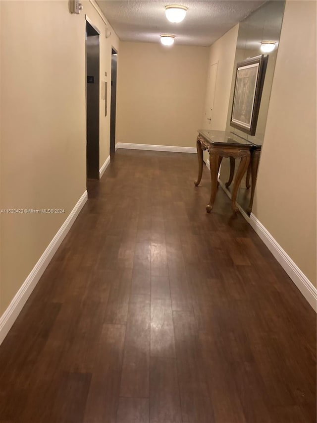 hallway featuring a textured ceiling and dark hardwood / wood-style floors