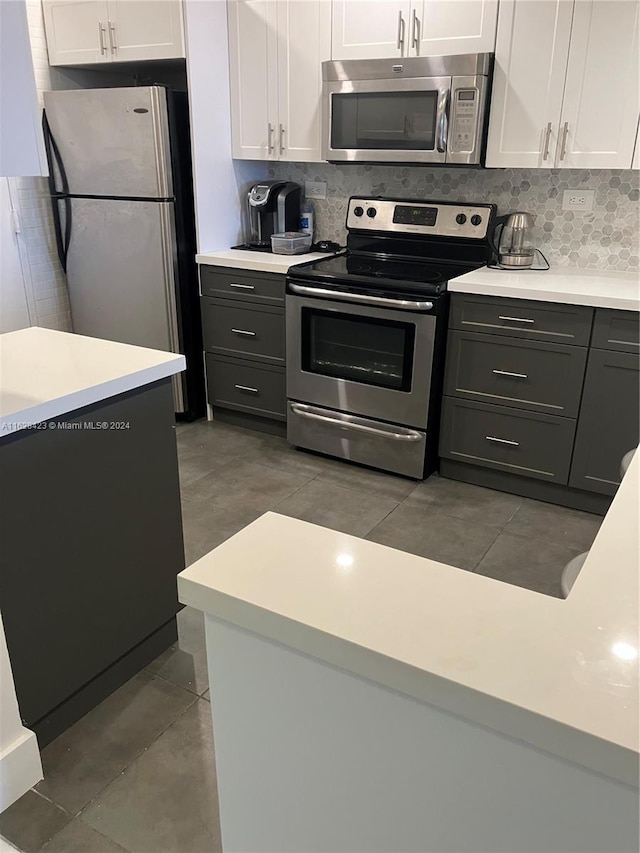 kitchen featuring white cabinetry, appliances with stainless steel finishes, gray cabinets, and backsplash