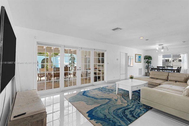 tiled living room with french doors and ceiling fan