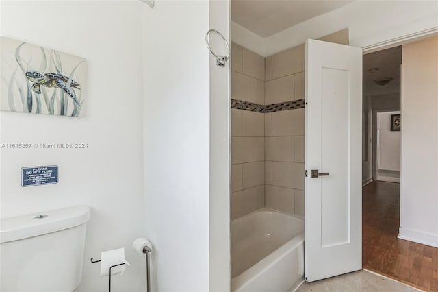 bathroom featuring hardwood / wood-style flooring, toilet, and tiled shower / bath