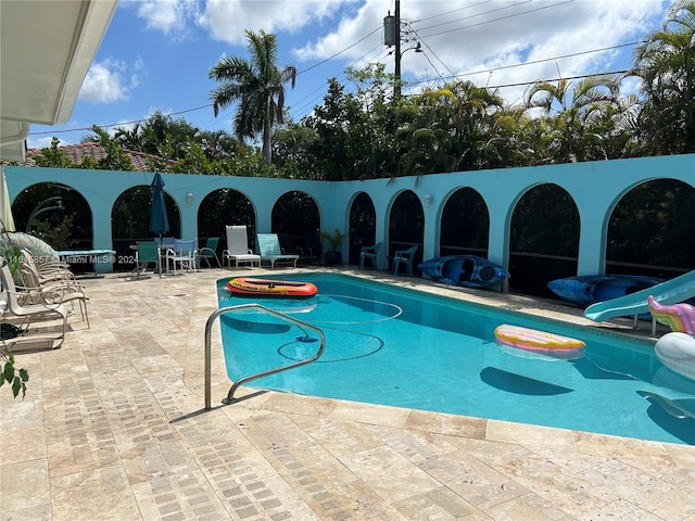 view of swimming pool with a water slide, a patio, and a jacuzzi