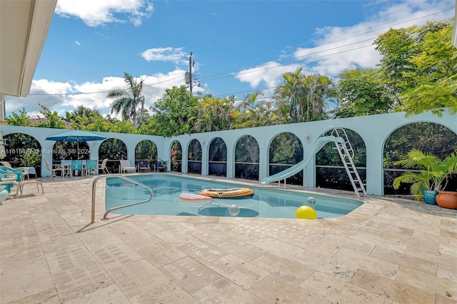 view of pool with a patio, a water slide, and a hot tub