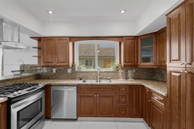 kitchen with wall chimney exhaust hood, sink, dishwasher, gas range oven, and light stone counters