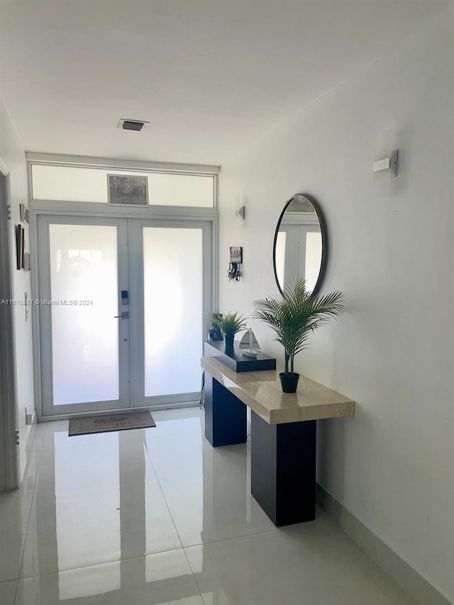 hallway with french doors, a wealth of natural light, and light tile patterned floors