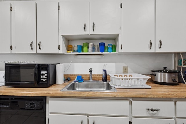 kitchen featuring sink, dishwashing machine, and white cabinets