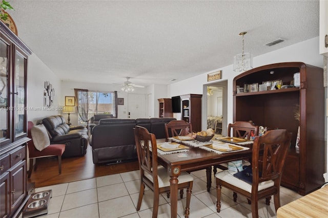 dining space featuring a textured ceiling, light tile patterned floors, and ceiling fan