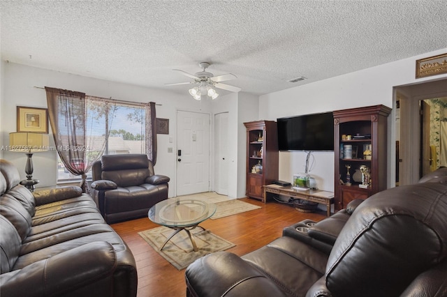 living room with a textured ceiling, hardwood / wood-style floors, and ceiling fan