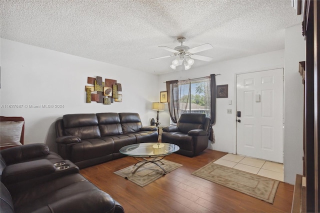 living room featuring a textured ceiling, light wood-type flooring, and ceiling fan