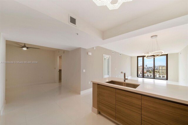 kitchen with ceiling fan with notable chandelier, light tile patterned floors, sink, and decorative light fixtures