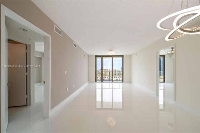 tiled spare room featuring a textured ceiling and floor to ceiling windows