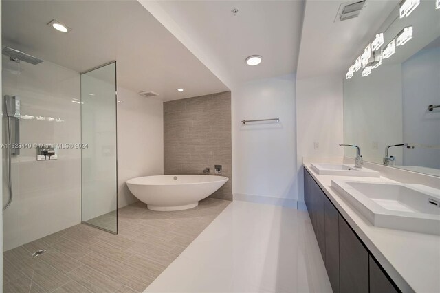 bathroom featuring tiled shower, dual bowl vanity, and tile patterned floors