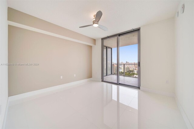 unfurnished room featuring ceiling fan, floor to ceiling windows, and light tile patterned floors