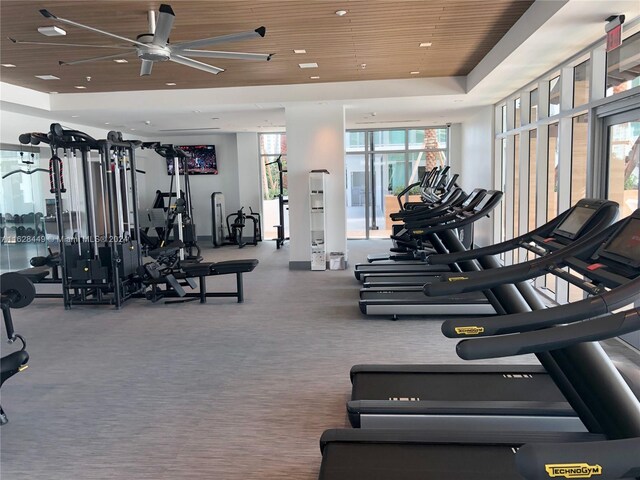 gym with ceiling fan, a tray ceiling, and wood ceiling