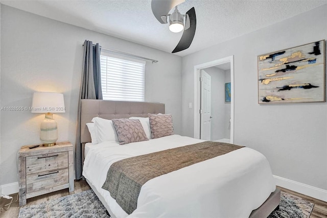 bedroom featuring ceiling fan, wood-type flooring, and a textured ceiling