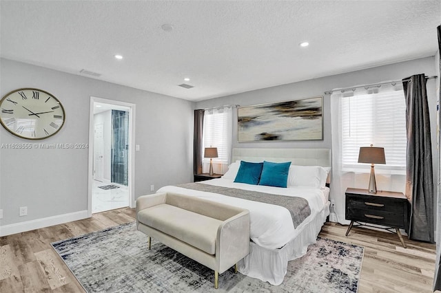 bedroom featuring a textured ceiling and light hardwood / wood-style flooring