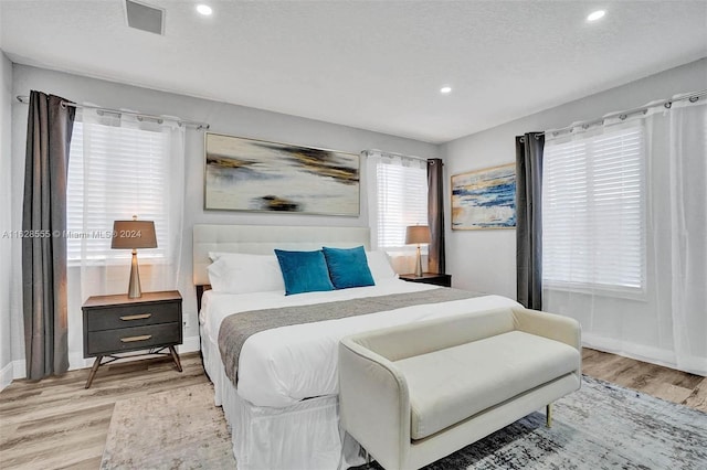 bedroom with light hardwood / wood-style floors and a textured ceiling