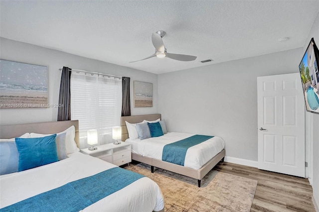 bedroom with ceiling fan, a textured ceiling, and light wood-type flooring