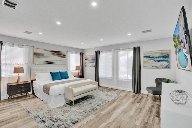 bedroom with multiple windows, a textured ceiling, and light hardwood / wood-style flooring