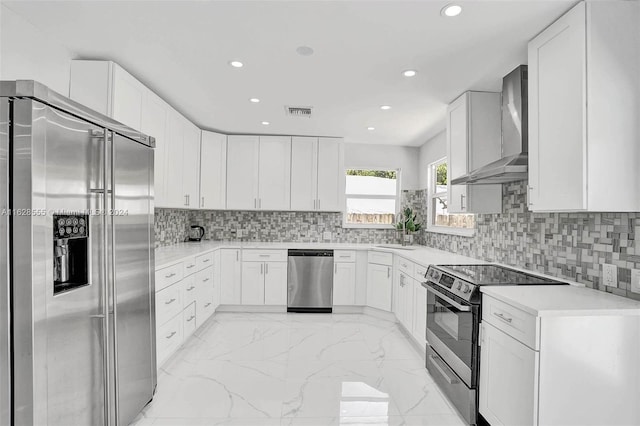 kitchen featuring wall chimney exhaust hood, sink, white cabinetry, and appliances with stainless steel finishes