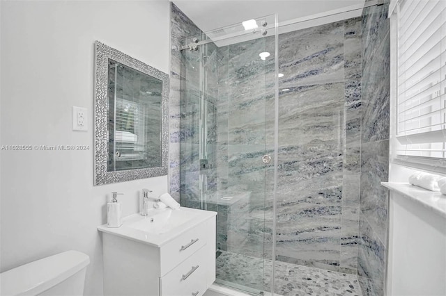 bathroom with vanity, toilet, and a shower with door