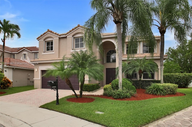 mediterranean / spanish-style house with a front yard, decorative driveway, and stucco siding