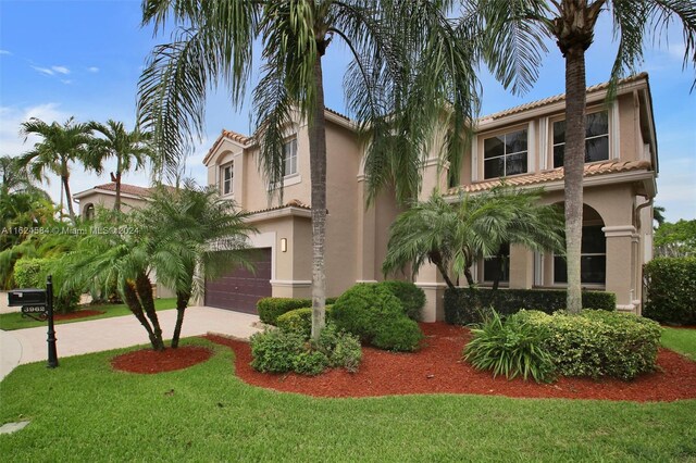 mediterranean / spanish home featuring a garage and a front yard