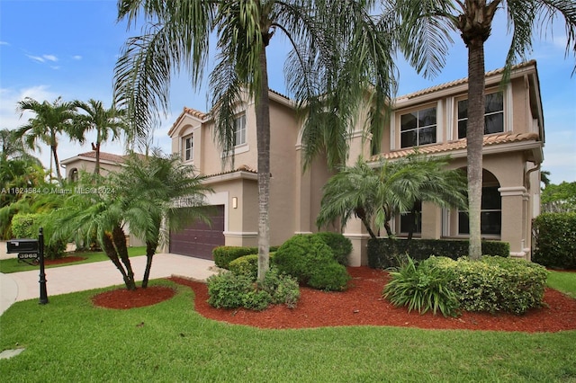 mediterranean / spanish house with a tiled roof, an attached garage, and stucco siding