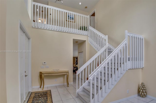 stairs with light tile patterned flooring and a high ceiling